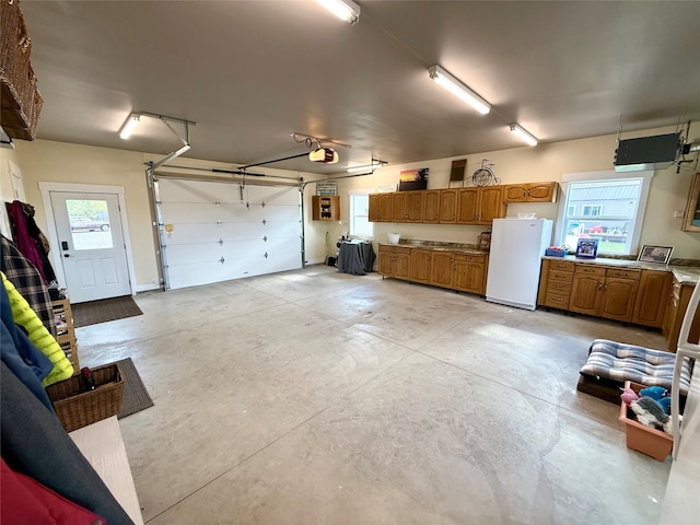 garage featuring white refrigerator and a garage door opener