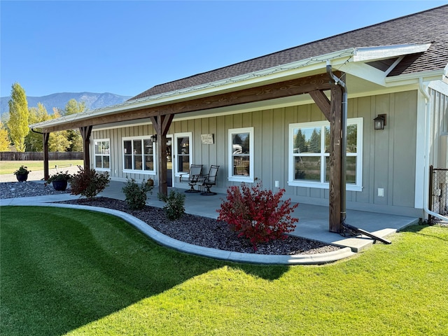 rear view of house with a yard, a mountain view, and a patio