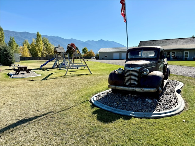 view of community with a playground, a lawn, and a mountain view