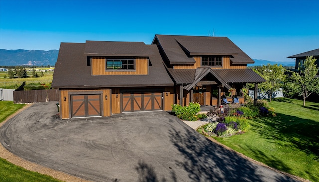 view of front facade featuring a garage, a mountain view, and a front lawn