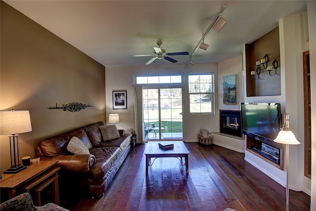 living room featuring dark wood-type flooring, rail lighting, and ceiling fan