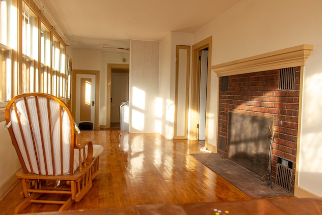 unfurnished room featuring wood-type flooring and a brick fireplace