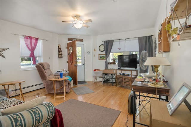 living room with ceiling fan, a wealth of natural light, baseboard heating, and light hardwood / wood-style flooring