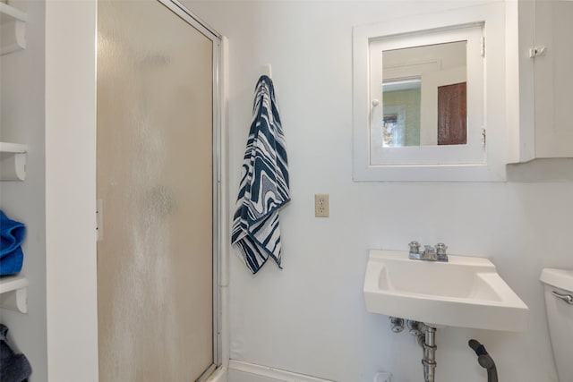 bathroom with toilet, an enclosed shower, and sink