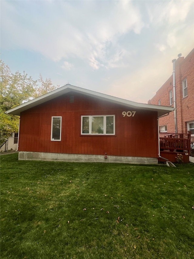 property exterior at dusk featuring a deck and a yard