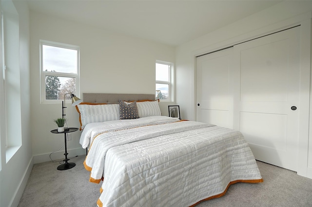 bedroom with multiple windows, light colored carpet, and a closet