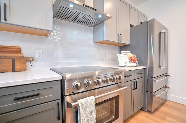 kitchen with gray cabinets, range hood, and stainless steel appliances