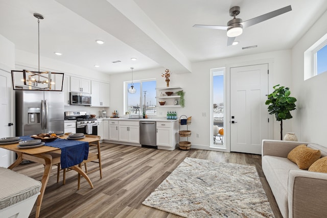 kitchen featuring light countertops, pendant lighting, white cabinets, stainless steel appliances, and light wood-type flooring