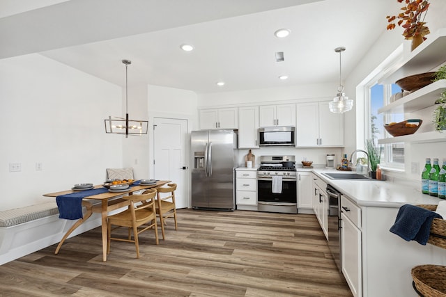 kitchen with light countertops, hanging light fixtures, stainless steel appliances, white cabinets, and breakfast area