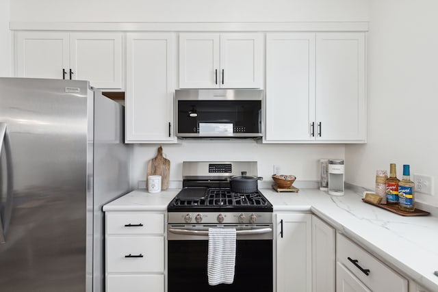 kitchen featuring appliances with stainless steel finishes, light stone countertops, and white cabinets