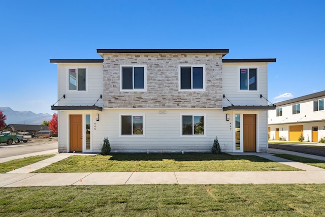 view of front of house featuring a front lawn, a mountain view, and stone siding