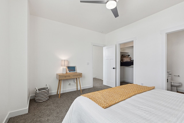 bedroom with ensuite bathroom, a ceiling fan, baseboards, dark colored carpet, and a spacious closet