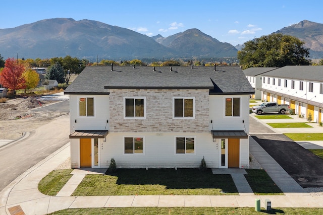 view of property featuring roof with shingles, a standing seam roof, a mountain view, and metal roof