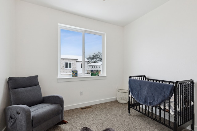 bedroom with baseboards, a nursery area, visible vents, and carpet