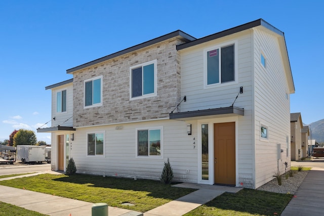 view of front of property with a front yard and stone siding