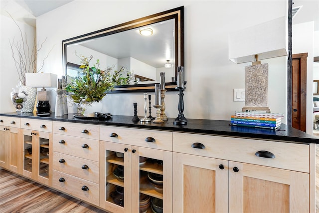 bar with light brown cabinetry and light hardwood / wood-style floors