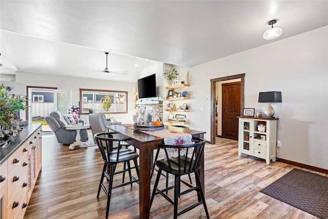 dining room featuring light wood-type flooring, vaulted ceiling, and ceiling fan