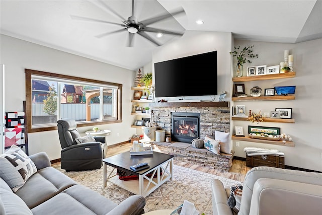 living room featuring ceiling fan, light hardwood / wood-style floors, a stone fireplace, and lofted ceiling