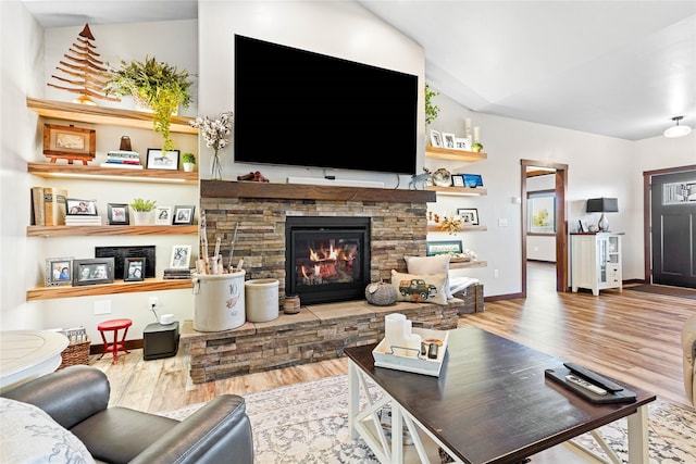 living room with lofted ceiling, a stone fireplace, and wood-type flooring