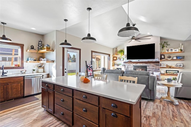 kitchen with lofted ceiling, a fireplace, stainless steel dishwasher, and decorative light fixtures