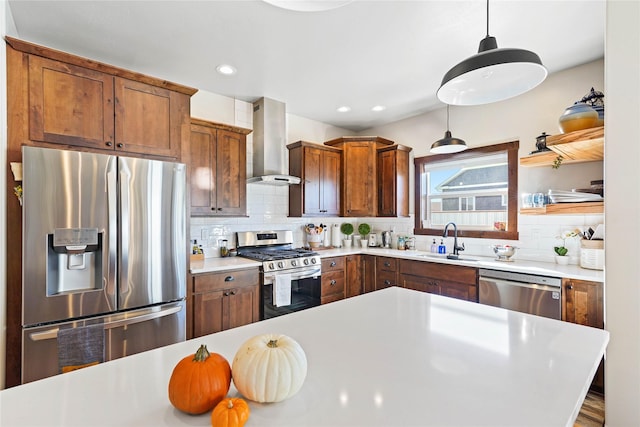 kitchen featuring wall chimney range hood, sink, hanging light fixtures, tasteful backsplash, and stainless steel appliances