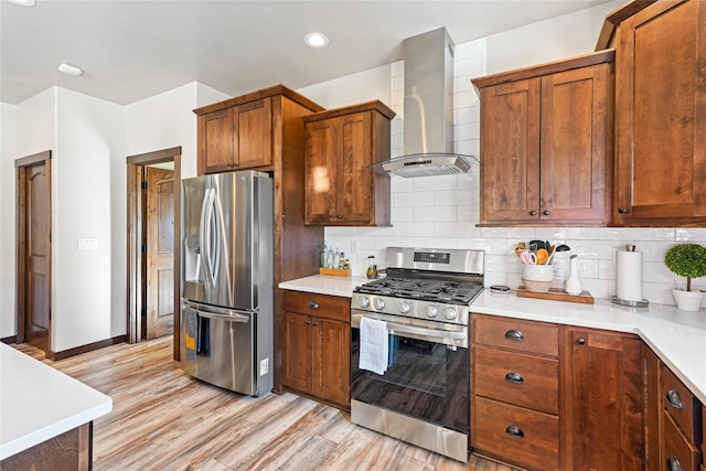 kitchen featuring decorative backsplash, stainless steel appliances, light hardwood / wood-style floors, and wall chimney range hood