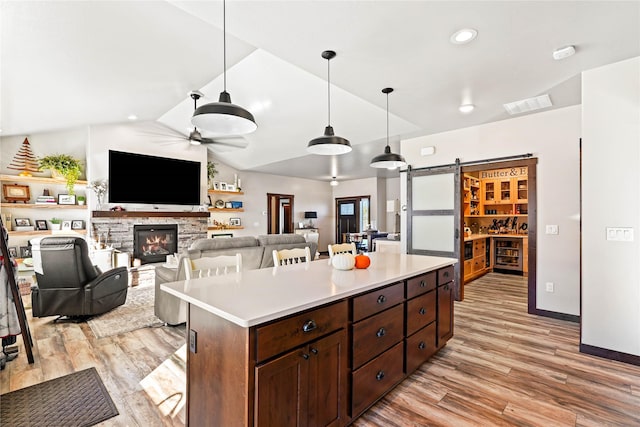 kitchen with ceiling fan, hanging light fixtures, a barn door, lofted ceiling, and a kitchen island