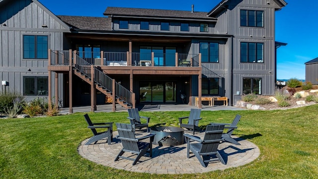 back of house with a patio, a lawn, stairway, board and batten siding, and a fire pit