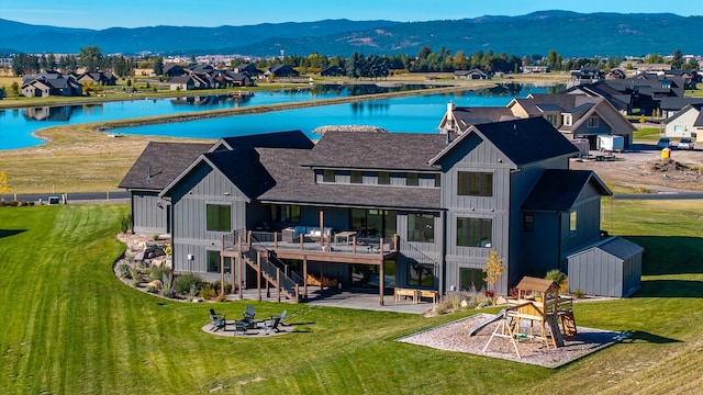 back of property with a patio, stairway, board and batten siding, a deck with water view, and a fire pit