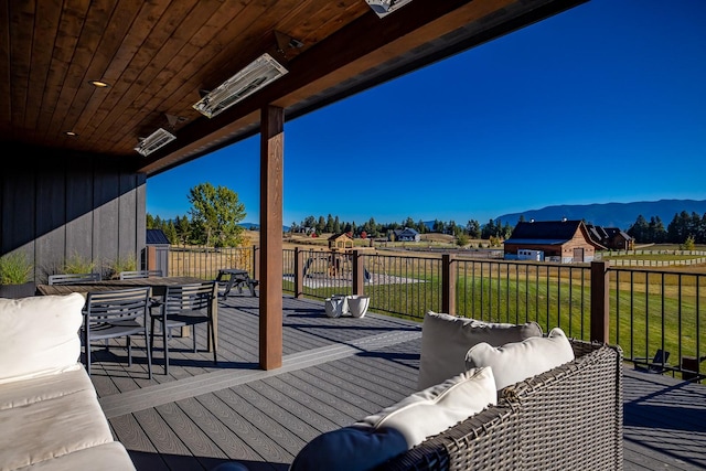 deck featuring a yard, outdoor dining space, a mountain view, and an outdoor living space