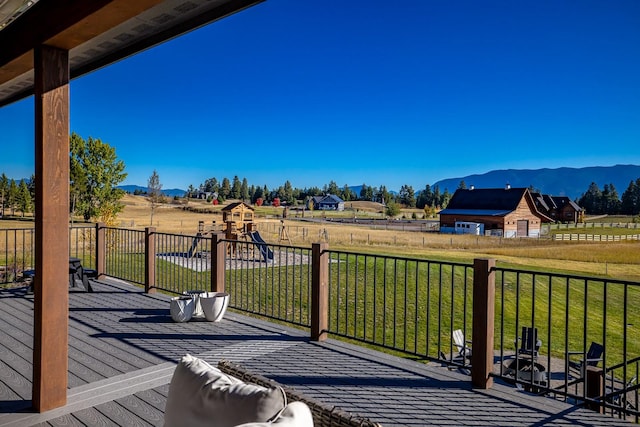 wooden terrace featuring a mountain view, a playground, and a yard