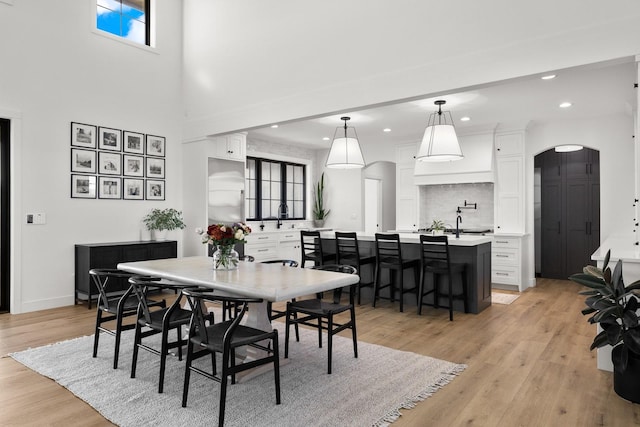 dining area featuring light wood-type flooring, baseboards, arched walkways, and recessed lighting