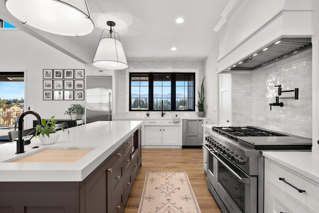 kitchen with premium range hood, light countertops, premium appliances, and white cabinets