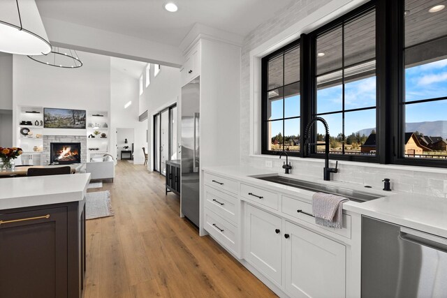 kitchen with light countertops, a sink, decorative light fixtures, and white cabinetry