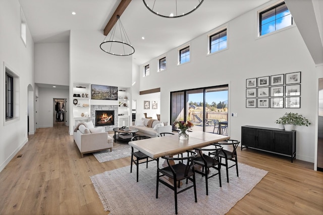 dining area featuring light wood-type flooring, a fireplace, beam ceiling, and baseboards