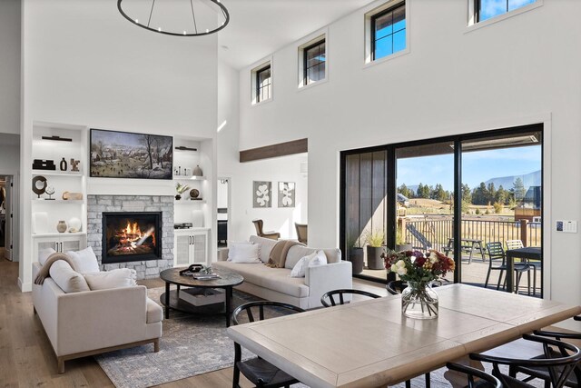 living room featuring built in features, a stone fireplace, and light wood-style flooring