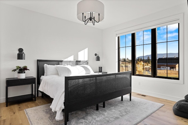 bedroom with visible vents, a mountain view, baseboards, and wood finished floors