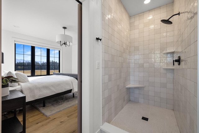 ensuite bathroom with ensuite bathroom, recessed lighting, wood finished floors, and a tile shower