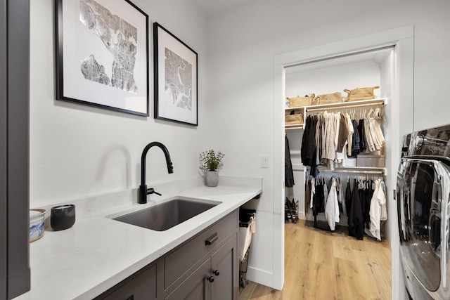 interior space featuring light wood-type flooring, a sink, and washer / dryer