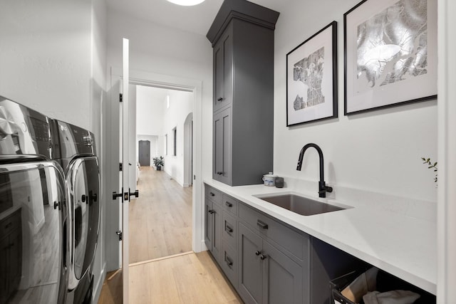 kitchen with gray cabinets, washer and dryer, light countertops, light wood-style floors, and a sink