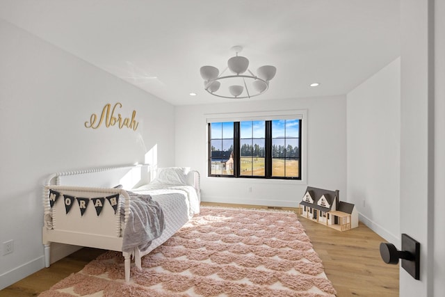 bedroom featuring a chandelier, recessed lighting, wood finished floors, and baseboards