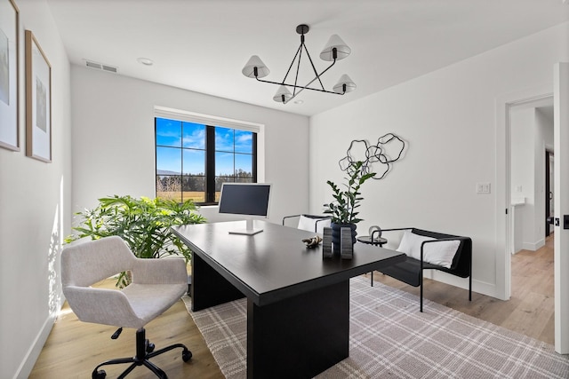 office space featuring light wood finished floors, baseboards, and visible vents