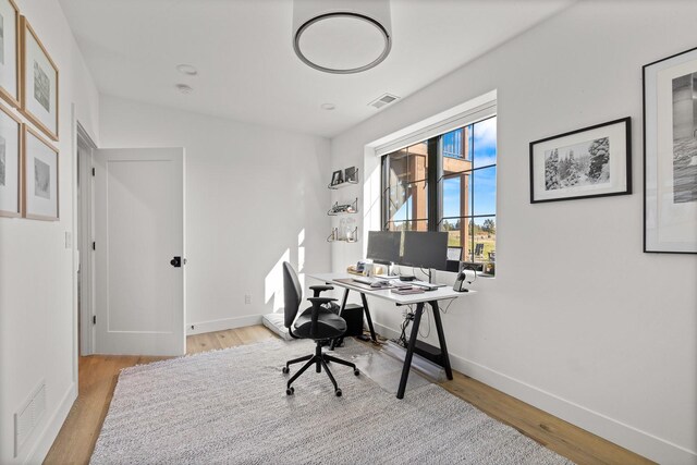 office with light wood finished floors, visible vents, and baseboards