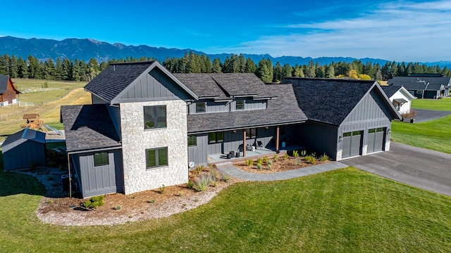 modern farmhouse featuring board and batten siding, stone siding, and a front lawn