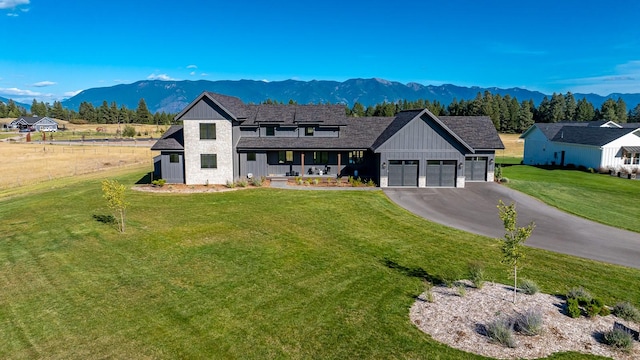 modern inspired farmhouse featuring an attached garage, a mountain view, driveway, a front lawn, and board and batten siding