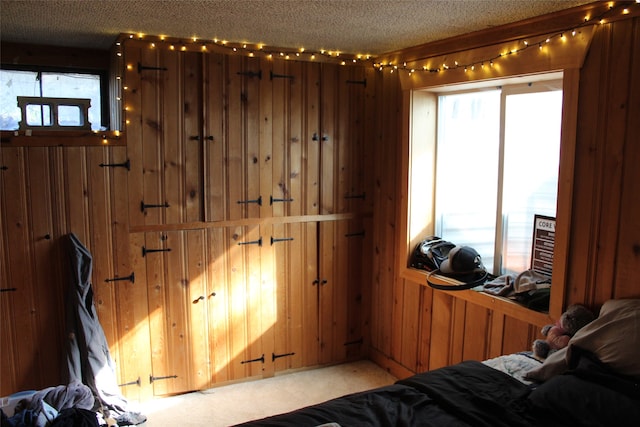 carpeted bedroom with wood walls and a textured ceiling