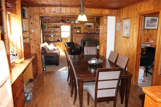 dining room with wooden walls, a fireplace, and wood ceiling