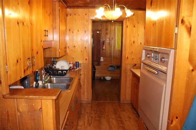 kitchen featuring pendant lighting, hardwood / wood-style flooring, wooden walls, and sink