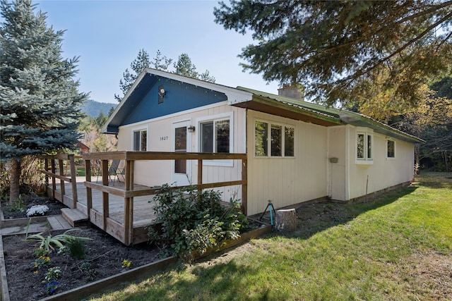 back of house featuring a deck and a lawn