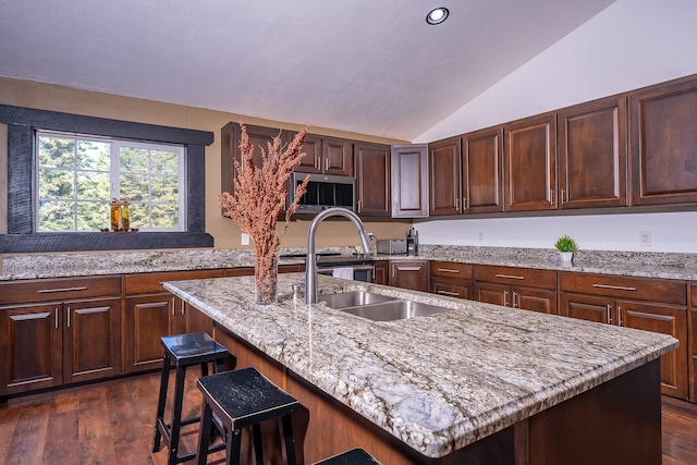 kitchen with a kitchen breakfast bar, dark wood-type flooring, light stone counters, lofted ceiling, and a center island